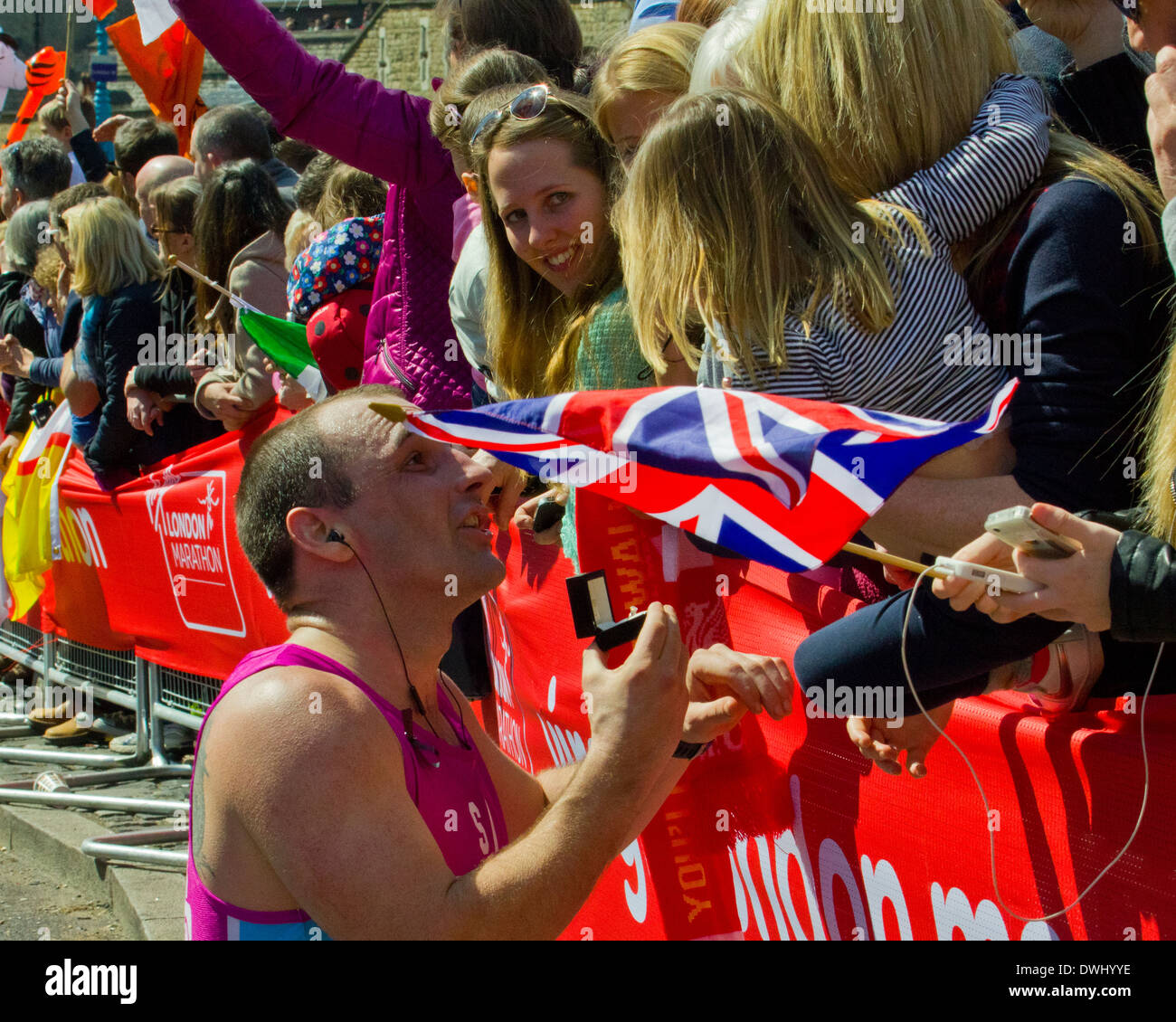 Läufer in den Virgin London Marathon 2013 auf halber Strecke auf einem Knie bekommt und seine Freundin schlägt. Stockfoto