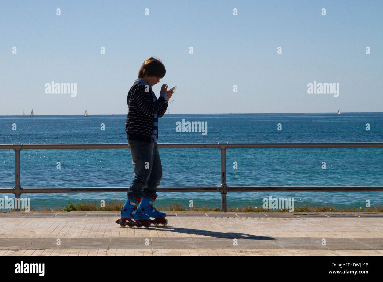 Kinder mit Handy Schlittschuhlaufen auf Rollerblades promenade Meerblick Palma De Mallorca Spanien Stockfoto