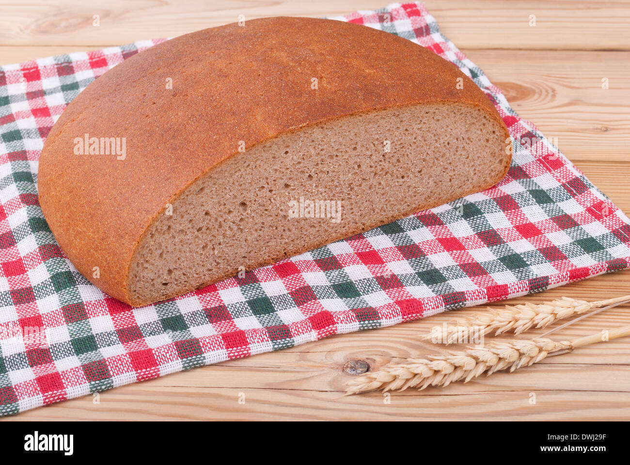 Laib Brot und Weizen Ohren auf einem Holztisch. Stockfoto