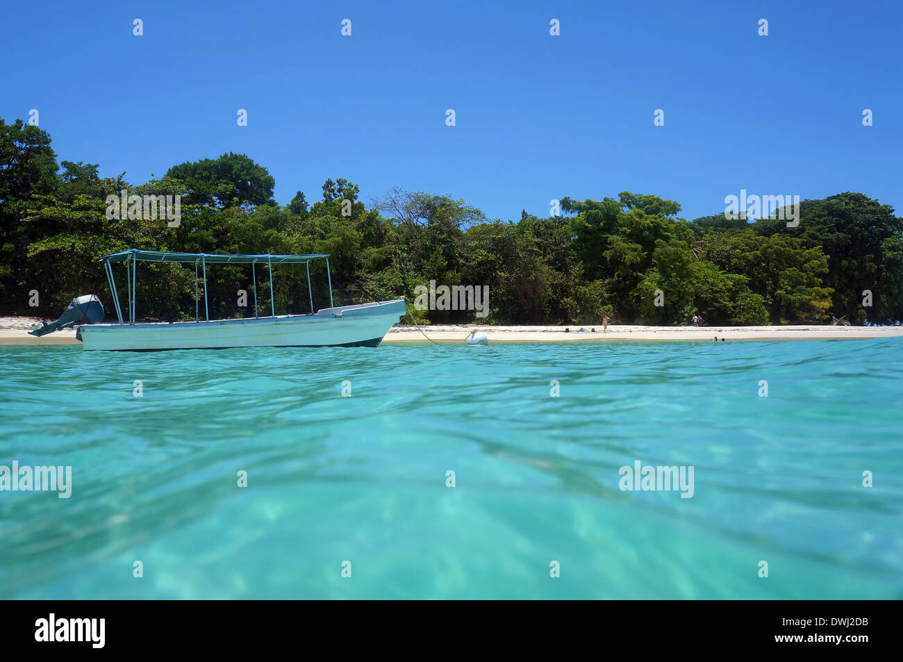 Von der Wasseroberfläche Boot am Liegeplatz Boje in der Nähe von einem unberührten tropischen Strand mit wenigen Touristen, Karibik Stockfoto