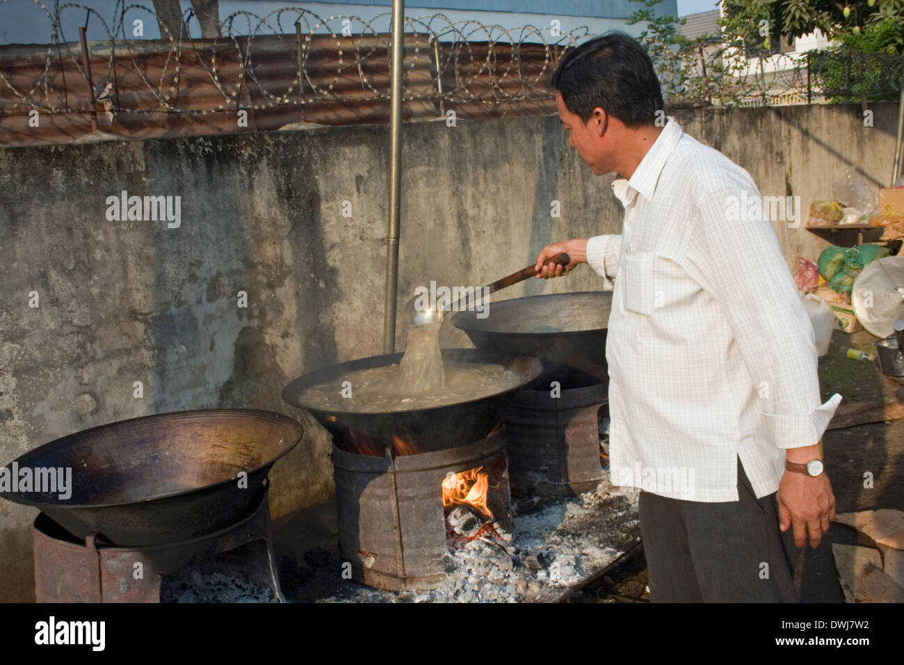 Ein Koch ist Suppe mit einer Kelle rühren, wie er traditionelle Khmer-Suppe in großer Wok auf einer Stadtstraße in Kampong Cham, Kambodscha kocht Stockfoto