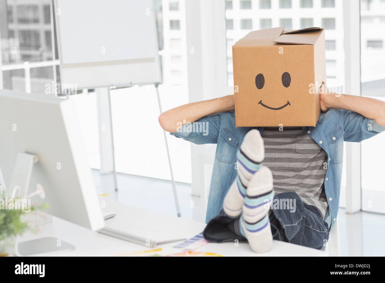 Legerer Mann mit glücklichen Smiley-Box über Gesicht im Büro Stockfoto