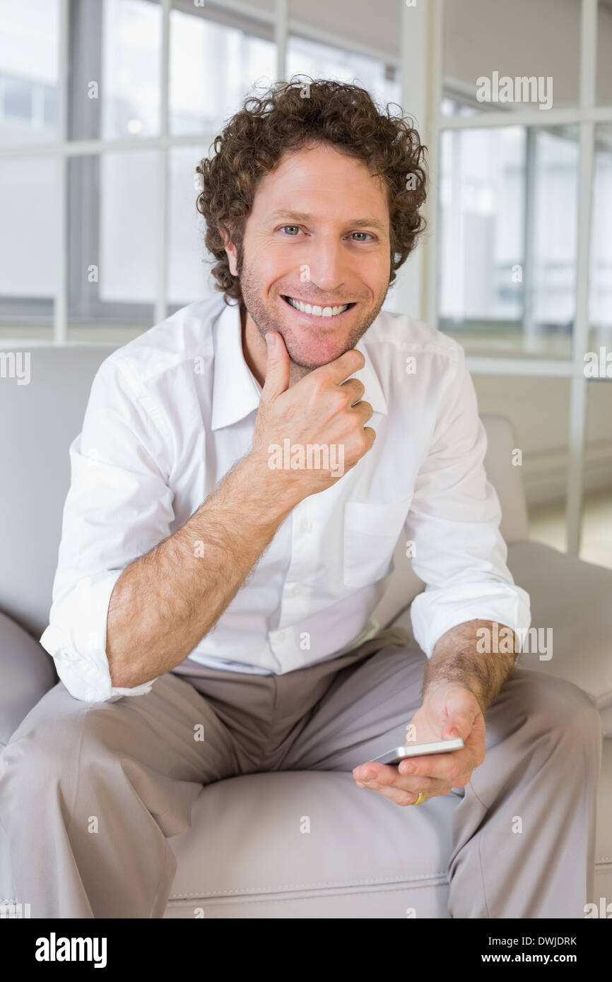 Gut gekleidete junge Mann sitzt zu Hause auf sofa Stockfoto
