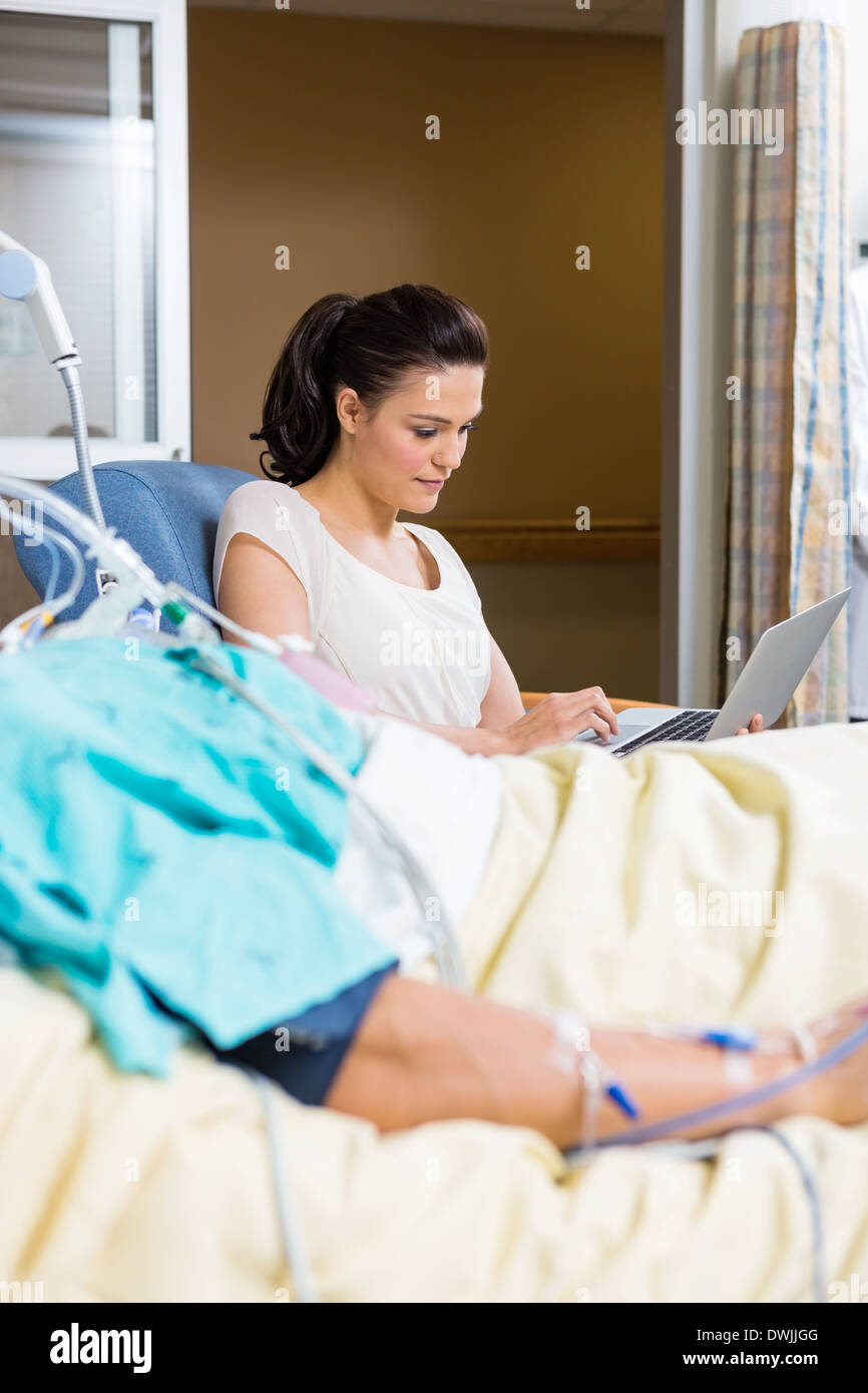 Frau mit Laptop sitzend durch Patienten Stockfoto