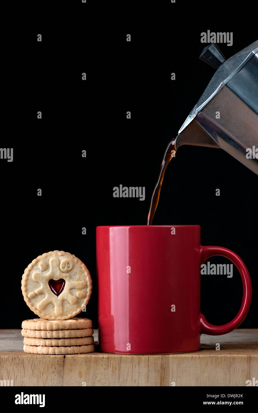 gießen Kaffee in einen roten Becher und Kekse Stockfoto