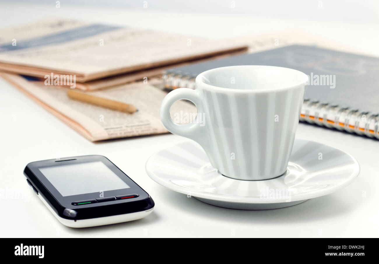Kaffeetasse mit Zeitung und Smartphone am Bürotisch Stockfoto