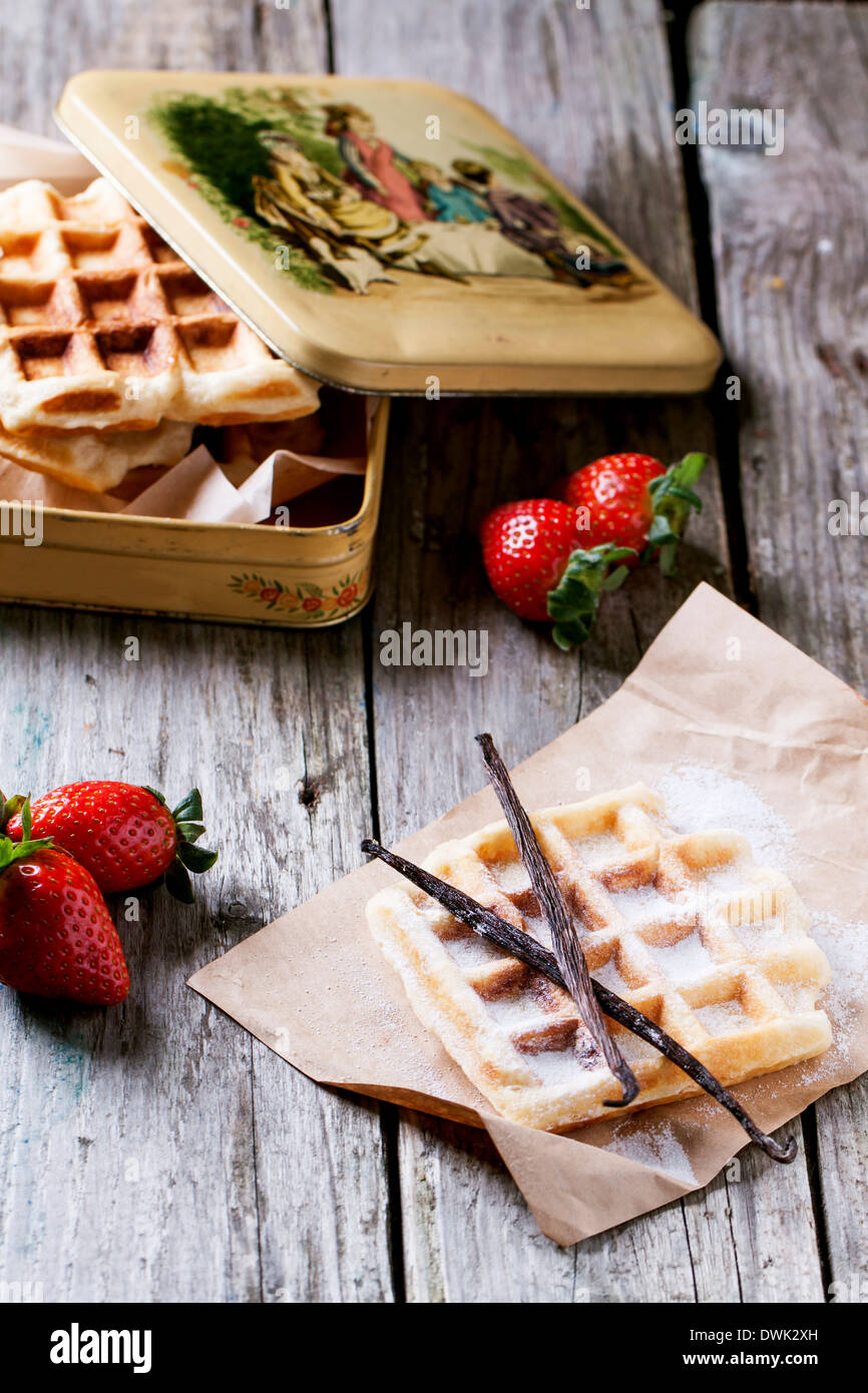 Frische Waffeln mit Vanille-Sticks und Erdbeeren serviert mit Vintage Metall-Box über alten Holztisch Stockfoto