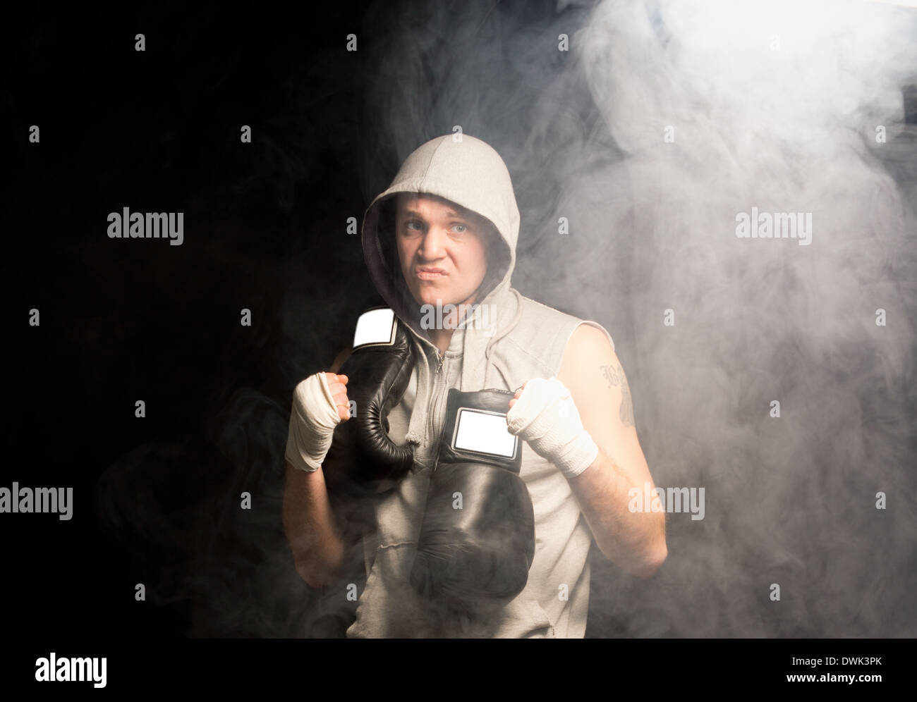 Meine schaut sich ambitionierte junge Boxer mitspielenden selbst bis vor einem Match biegen seine Faust und knurrend in einer dunklen rauchigen Atmosphäre Stockfoto