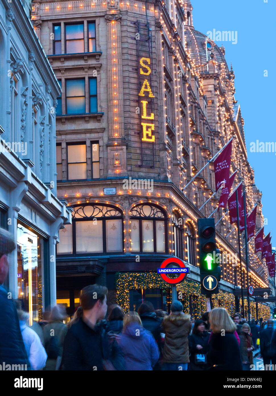 Harrods Kaufhaus in der Abenddämmerung mit beleuchteten "Sale" Schild und Massen von Käufern Knightsbridge London SW1 Stockfoto