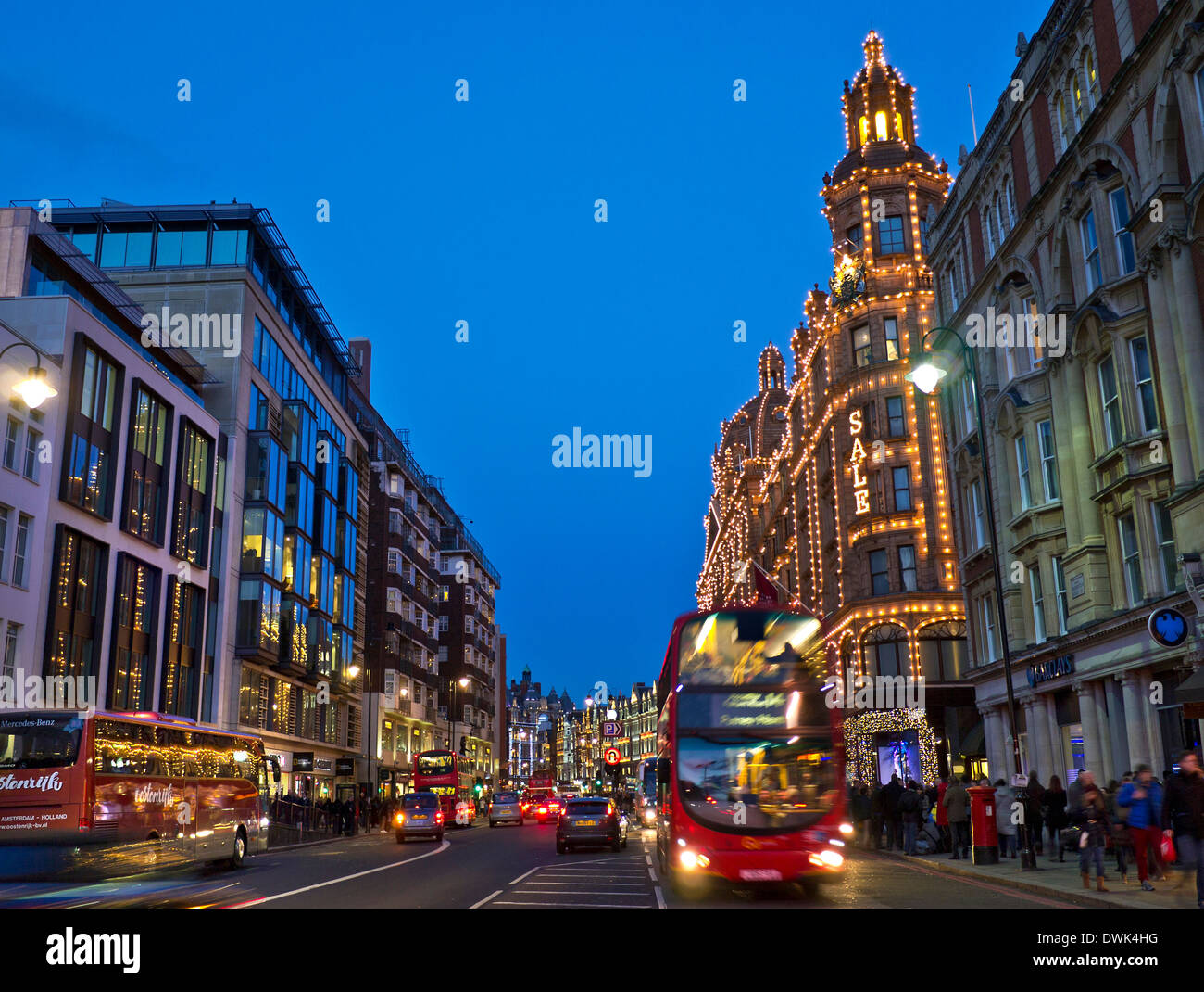 Brompton Road und Harrods Kaufhaus in der Abenddämmerung mit beleuchteten "Sale" Schild Shopper rote Busse und taxis Knightsbridge London SW1 Stockfoto