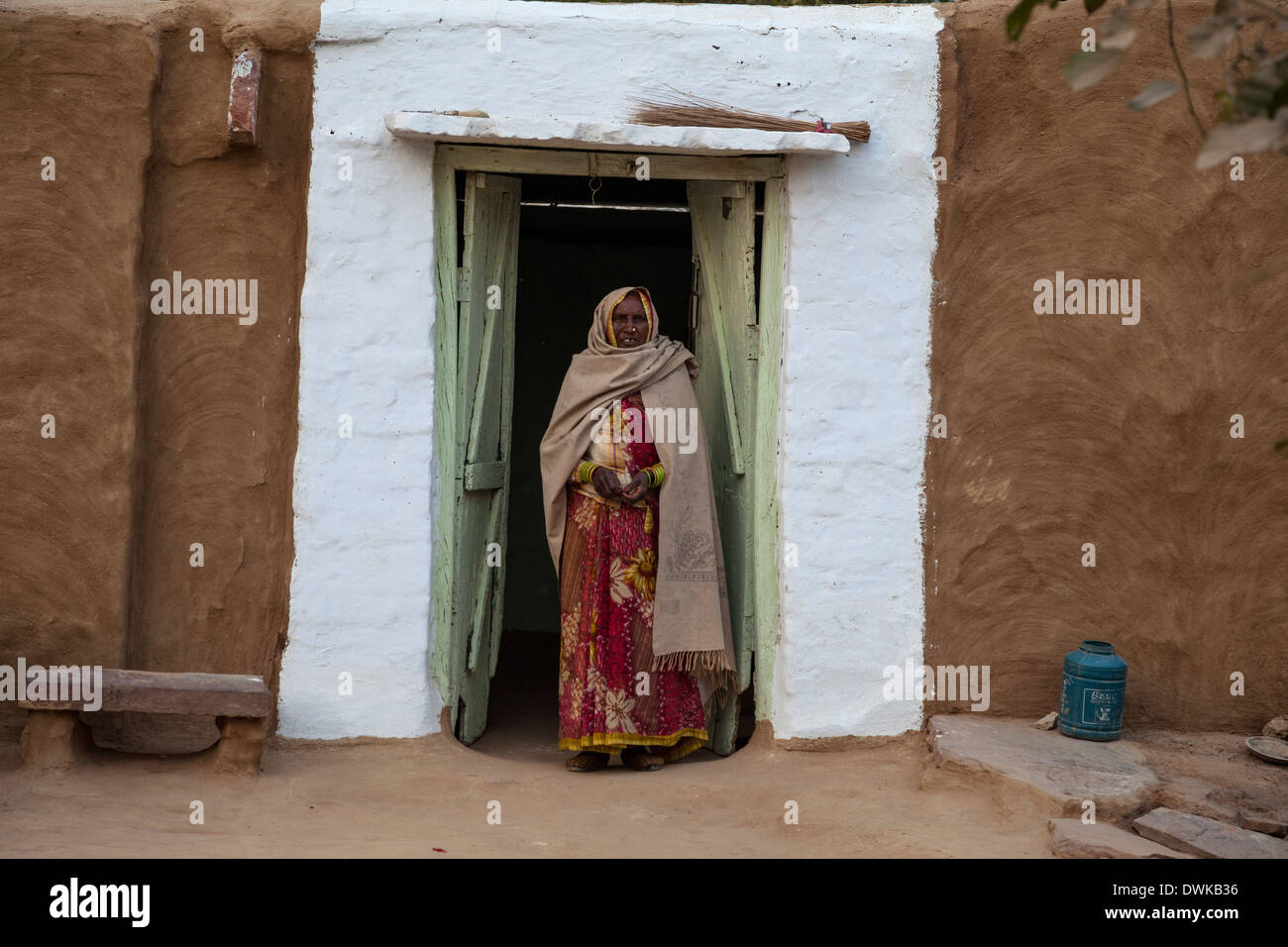 Bharatpur, Rajasthan, Indien. Alte Frau steht in der Tür ihres Hauses. Eine Dupatta (Schal) deckt ihr Kopf und Ihre Schultern. Stockfoto
