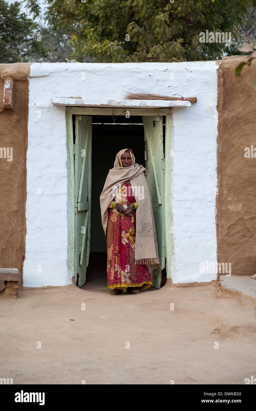 Bharatpur, Rajasthan, Indien. Alte Frau steht in der Tür ihres Hauses. Eine Dupatta (Schal) deckt ihr Kopf und Ihre Schultern. Stockfoto