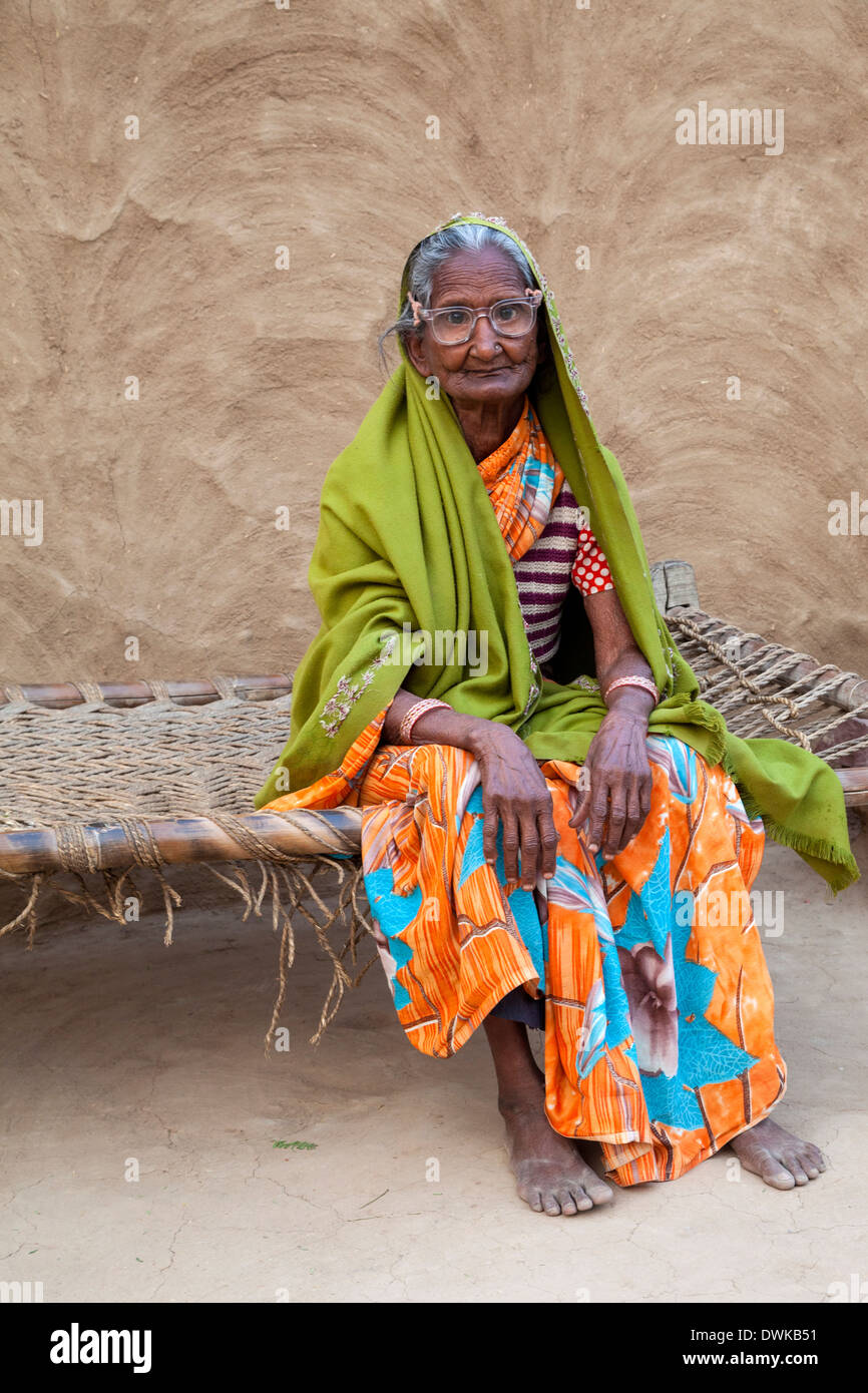 Bharatpur, Rajasthan, Indien. Alte Frau sitzt vor ihrem Haus. Sie trägt eine Dupatta (Schal) über ihren Kopf und Ihre Schultern. Stockfoto