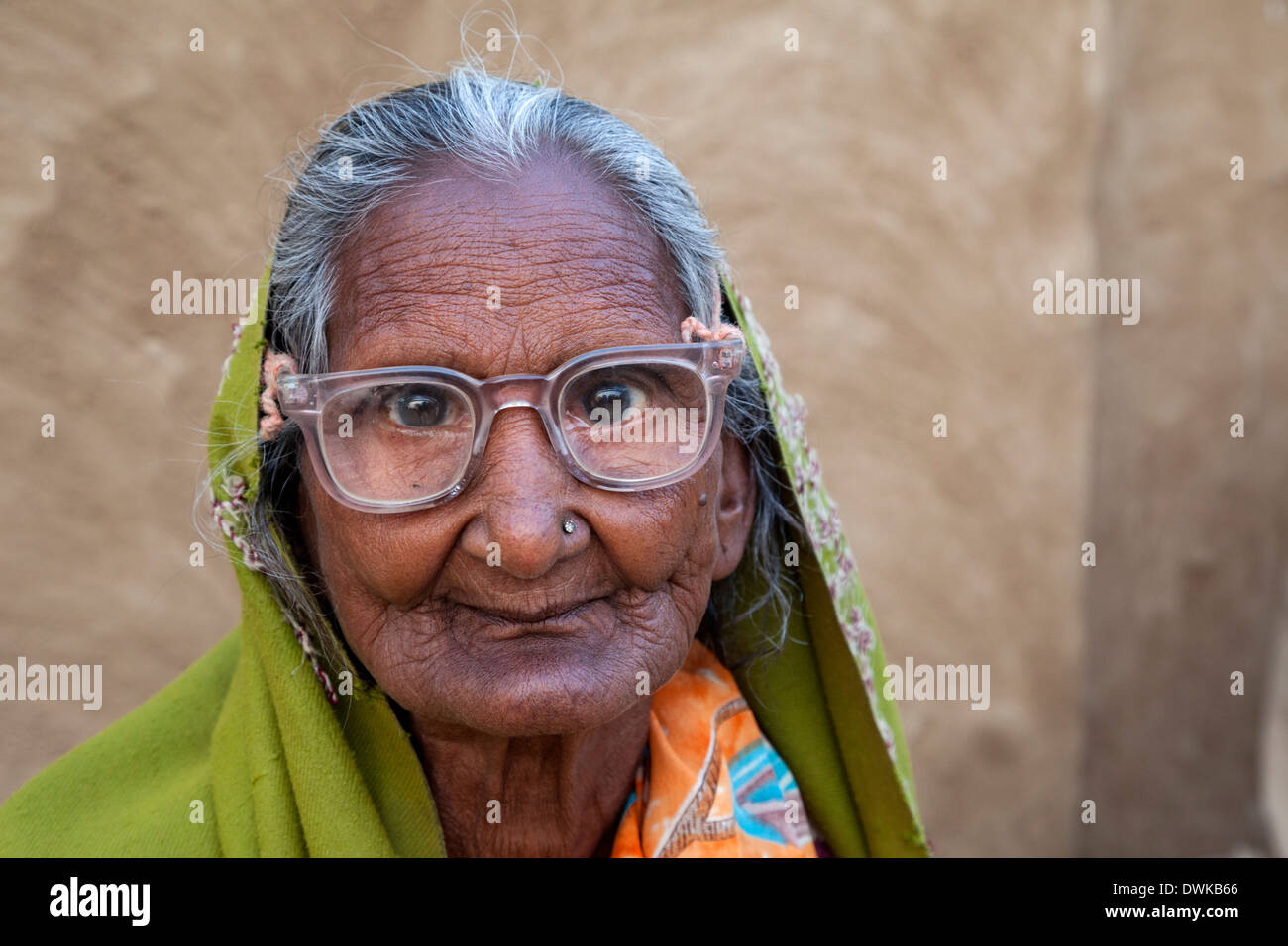 Bharatpur, Rajasthan, Indien. Alte Frau sitzt vor ihrem Haus. Sie trägt eine Dupatta (Schal) über ihren Kopf und Ihre Schultern. Stockfoto