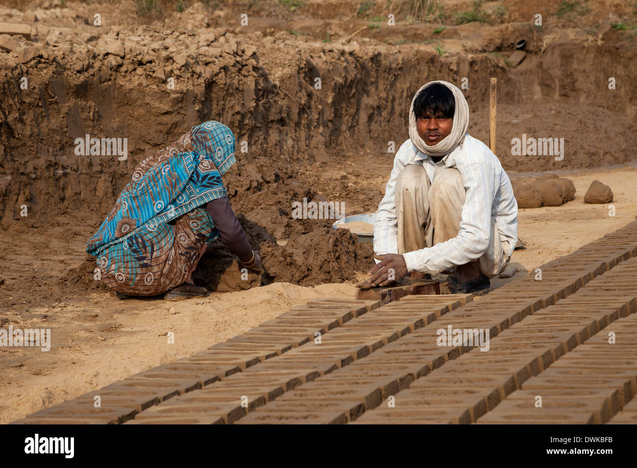 Rajasthan, Indien. Frau bereitet weichen Schlamm während Mann es in Ziegel Formen ausdrückt. Stockfoto