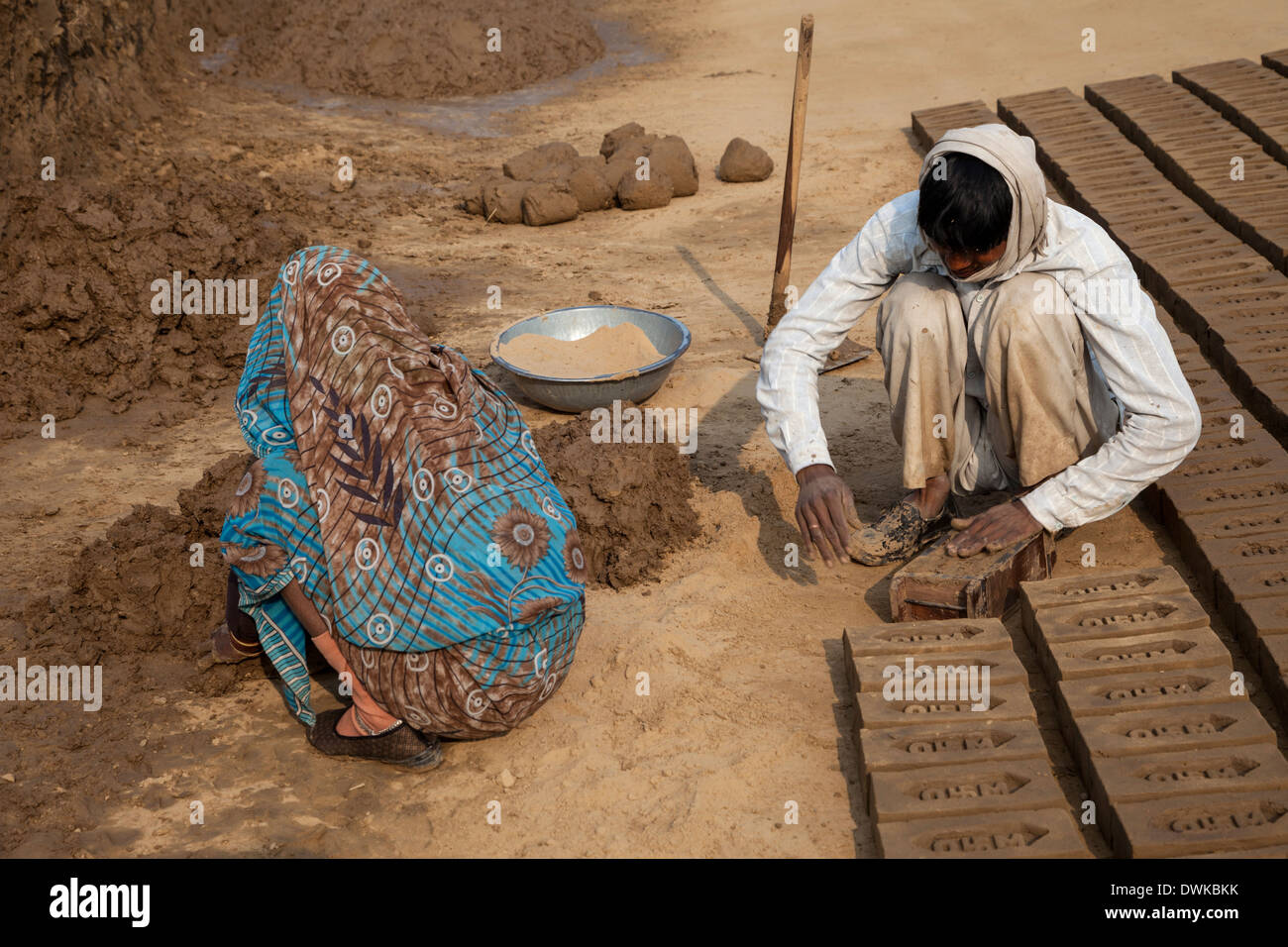 Rajasthan, Indien. Ehemann glättet Schlamm in Brick Mold bevor es umzudrehen während Frau bereitet Schlamm für den nächsten Stein. Stockfoto