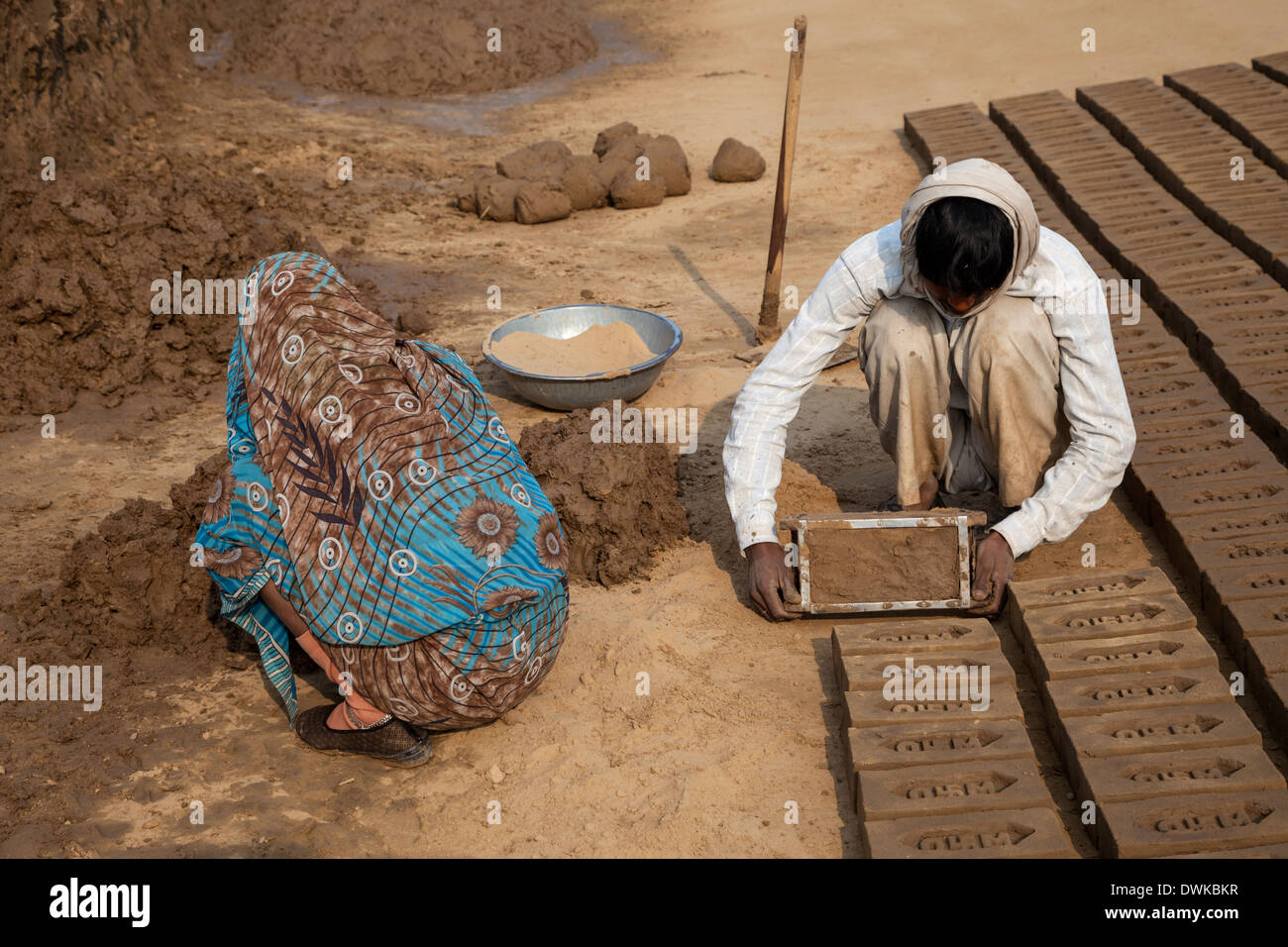 Rajasthan, Indien. Mann macht Brick Mold über während Frau bereitet Schlamm für den nächsten Stein. Stockfoto