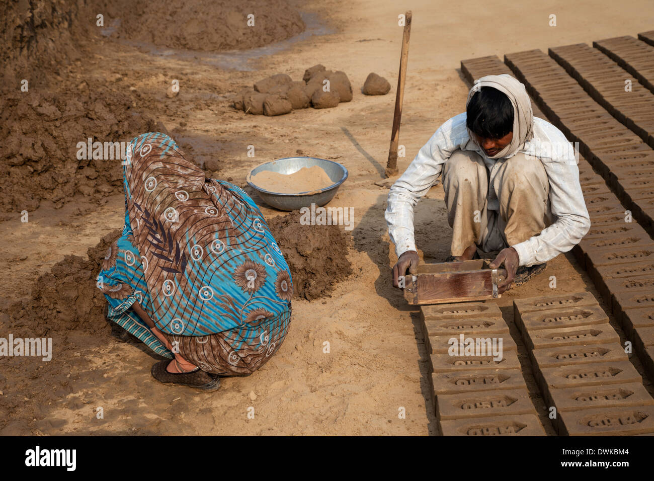 Rajasthan, Indien. Mann entfernt Schimmel aus Backstein und Frau bereitet Schlamm für den nächsten Stein. Stockfoto
