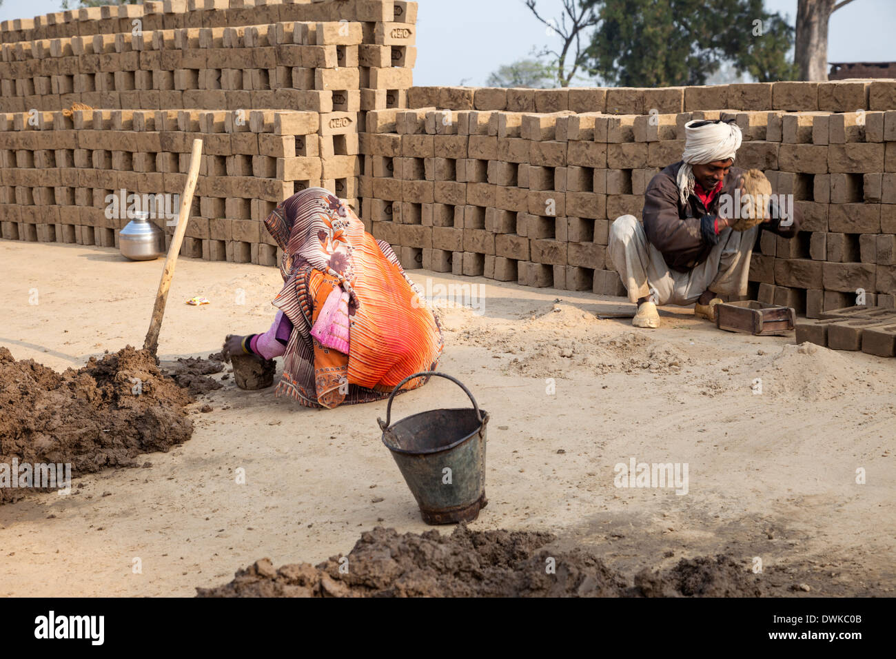 Rajasthan, Indien. Frau bereitet weichen Schlamm während Mann es in Ziegel Formen ausdrückt. Stockfoto