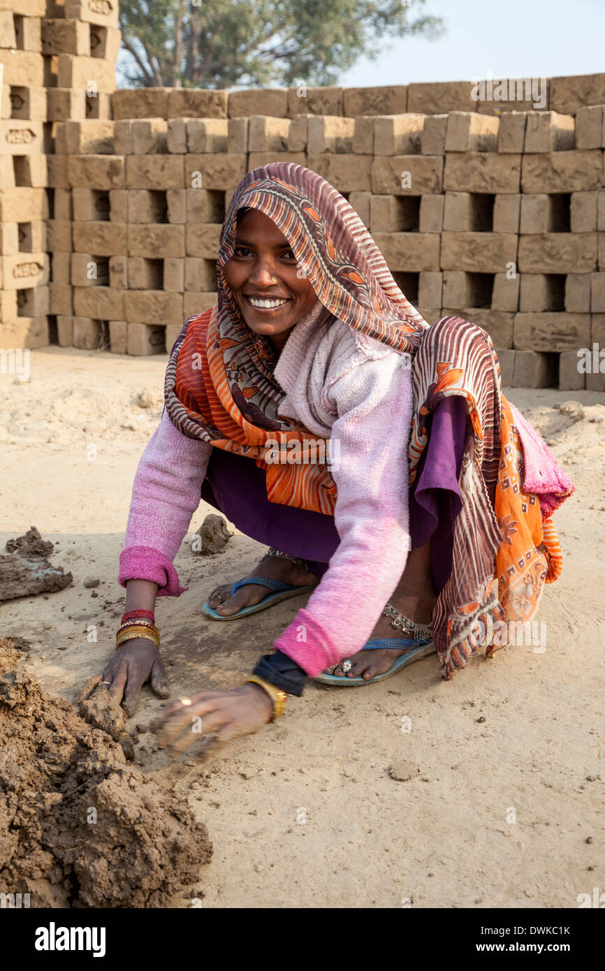 Rajasthan, Indien. Frau Vorbereitung Schlamm für Ehemann in die Ziegel Formen umzusetzen. Beachten Sie die Zehenringe und Fußkettchen. Stockfoto