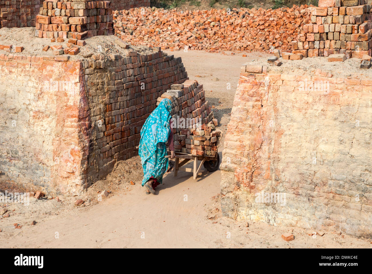 Rajasthan, Indien. Frau Schubkarre Steine an einem Speicherort auf Transport zum Markt zu warten. Stockfoto