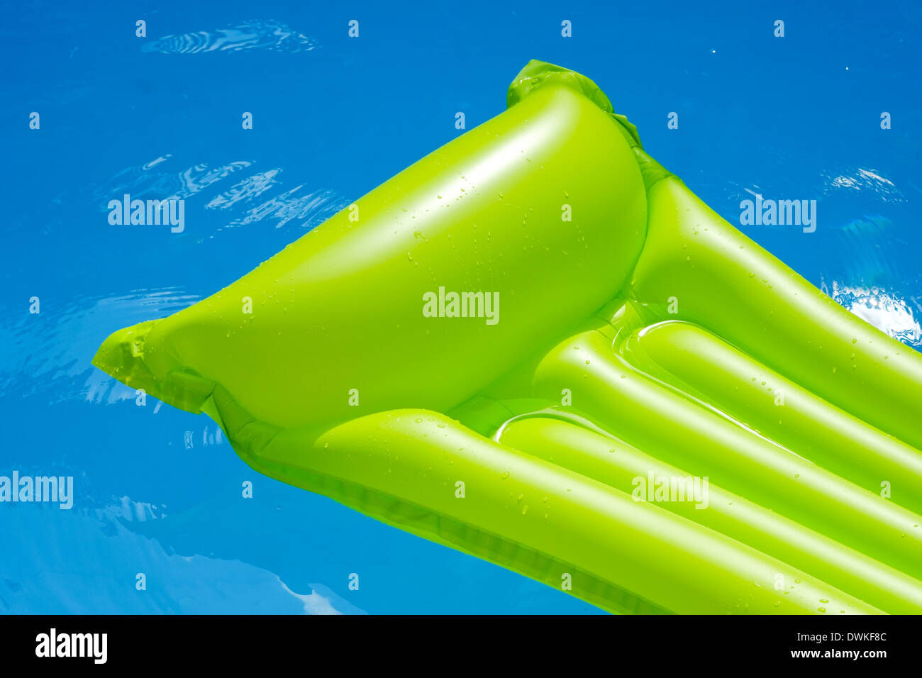grüne Luftmatratze schwimmt im blauen Wasser eines Schwimmbades. aufblasbare wird nur teilweise angezeigt Stockfoto