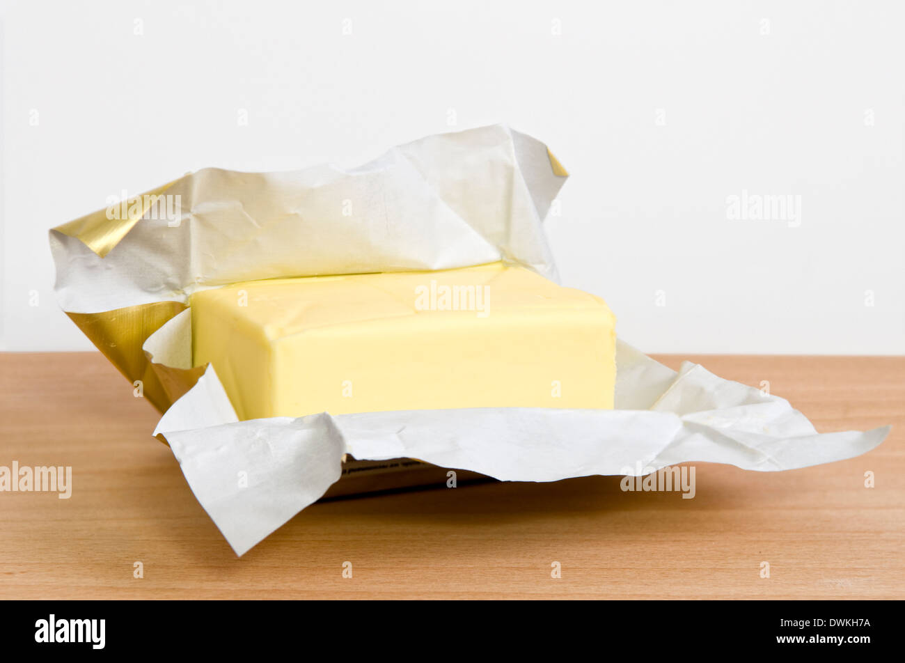 Offene Packung Butter auf Schneidbrett aus Holz Stockfoto