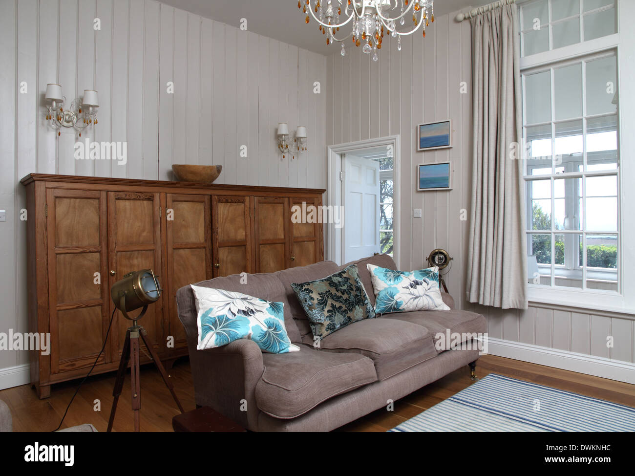 Wohnzimmer mit großen Anrichte aus Holz, Beige Sofa, Holzboden mit Teppich. Große Schiebefenster Stockfoto