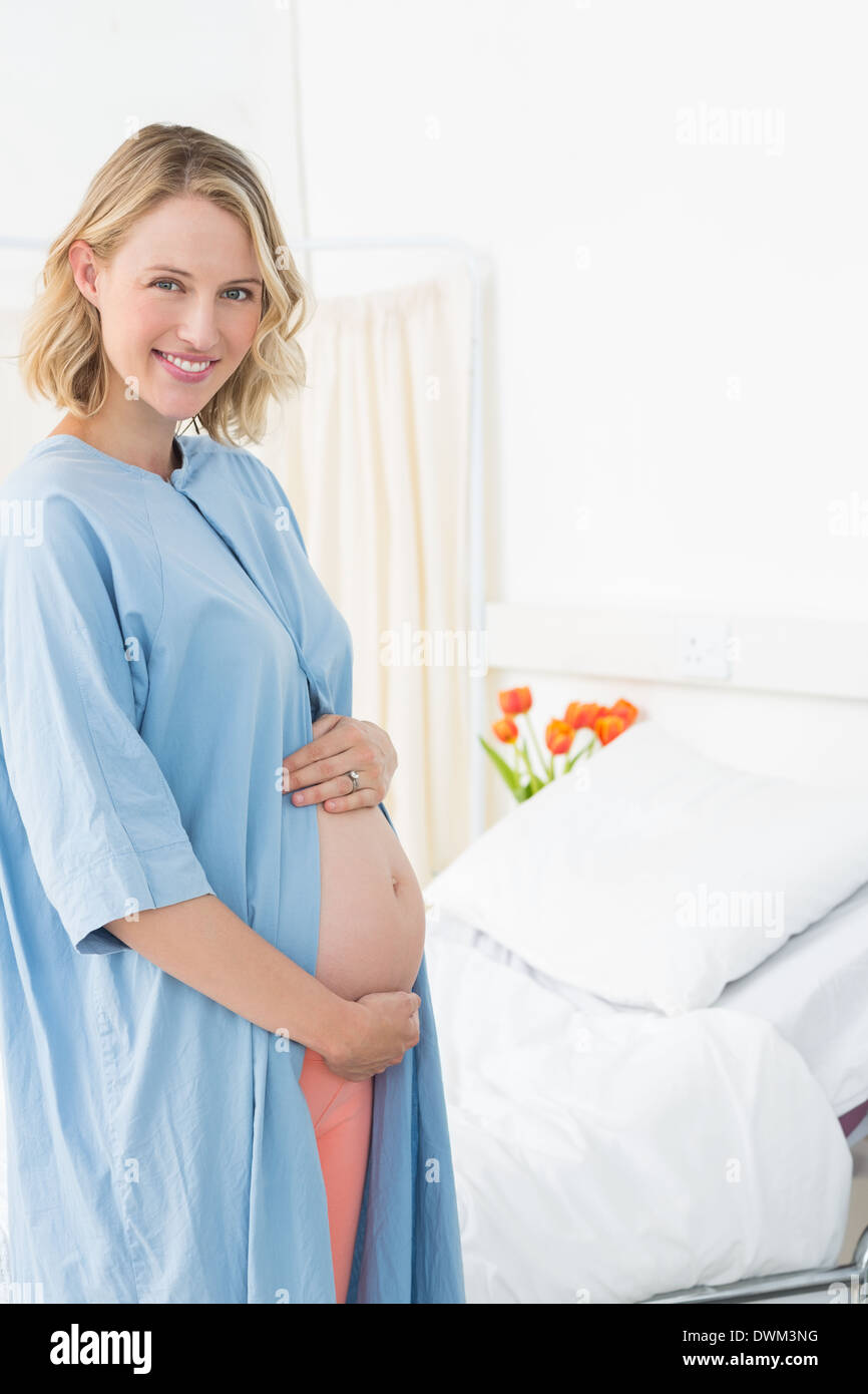 Glücklich schwanger Frau trägt Krankenhemd Stockfoto