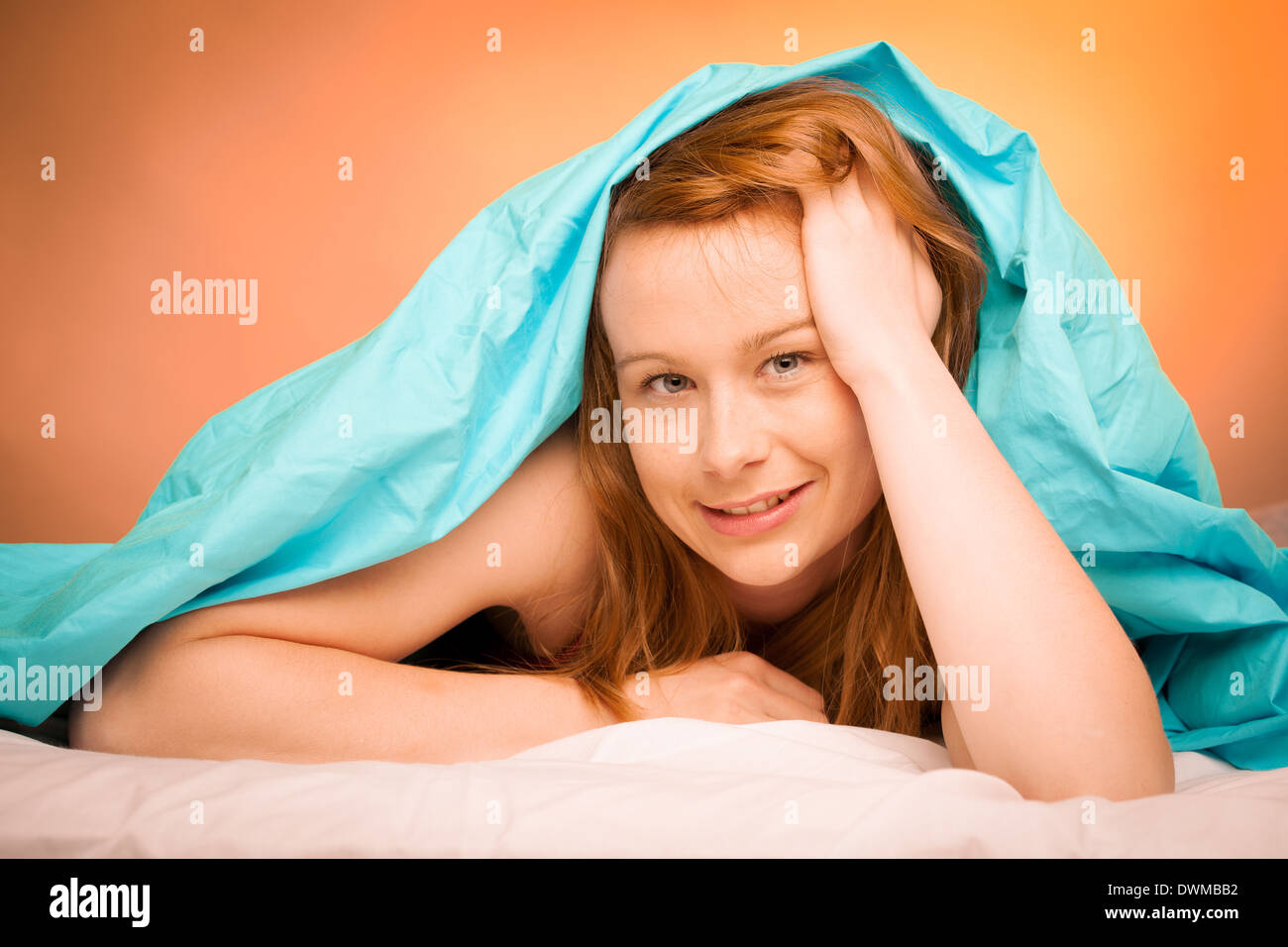 Frau liegend auf Kissen im Bett, bedeckt mit blauen Decke Stockfoto