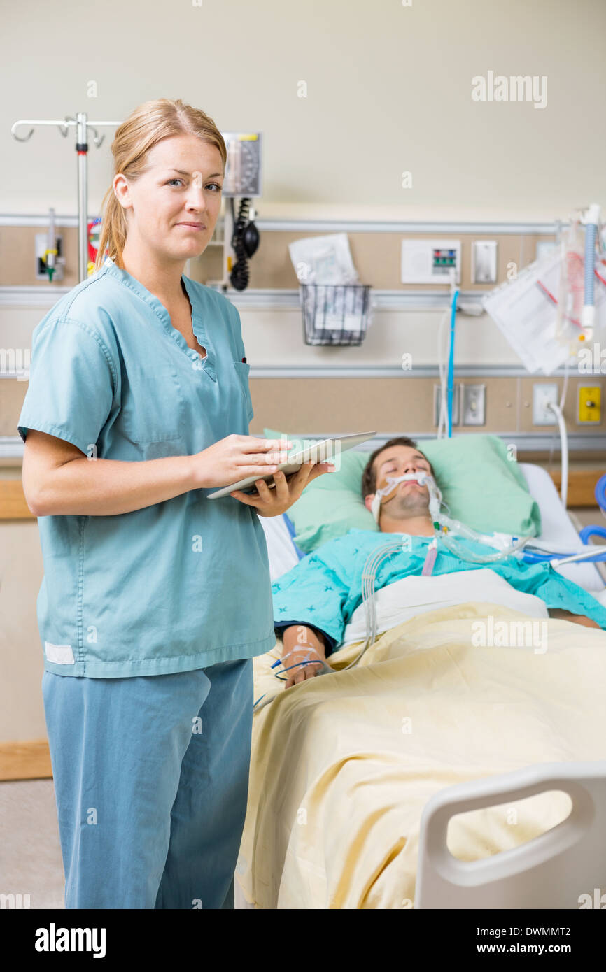 Krankenschwester mit Digital-Tablette beim männlichen Patienten Ausruhen auf Bett Stockfoto