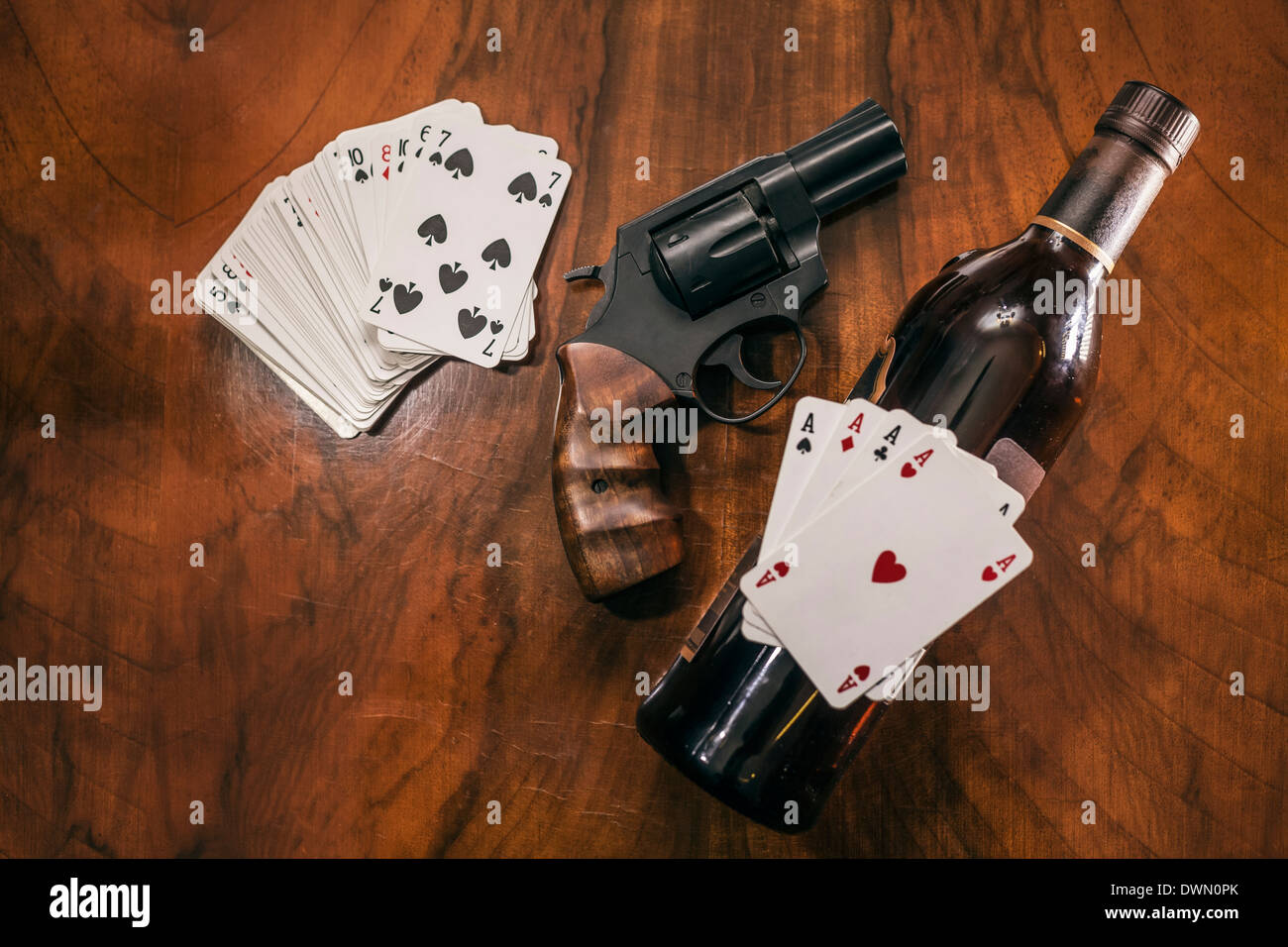 Spielkarten mit Pistole und eine Flasche Alkohol auf den Tisch  Stockfotografie - Alamy