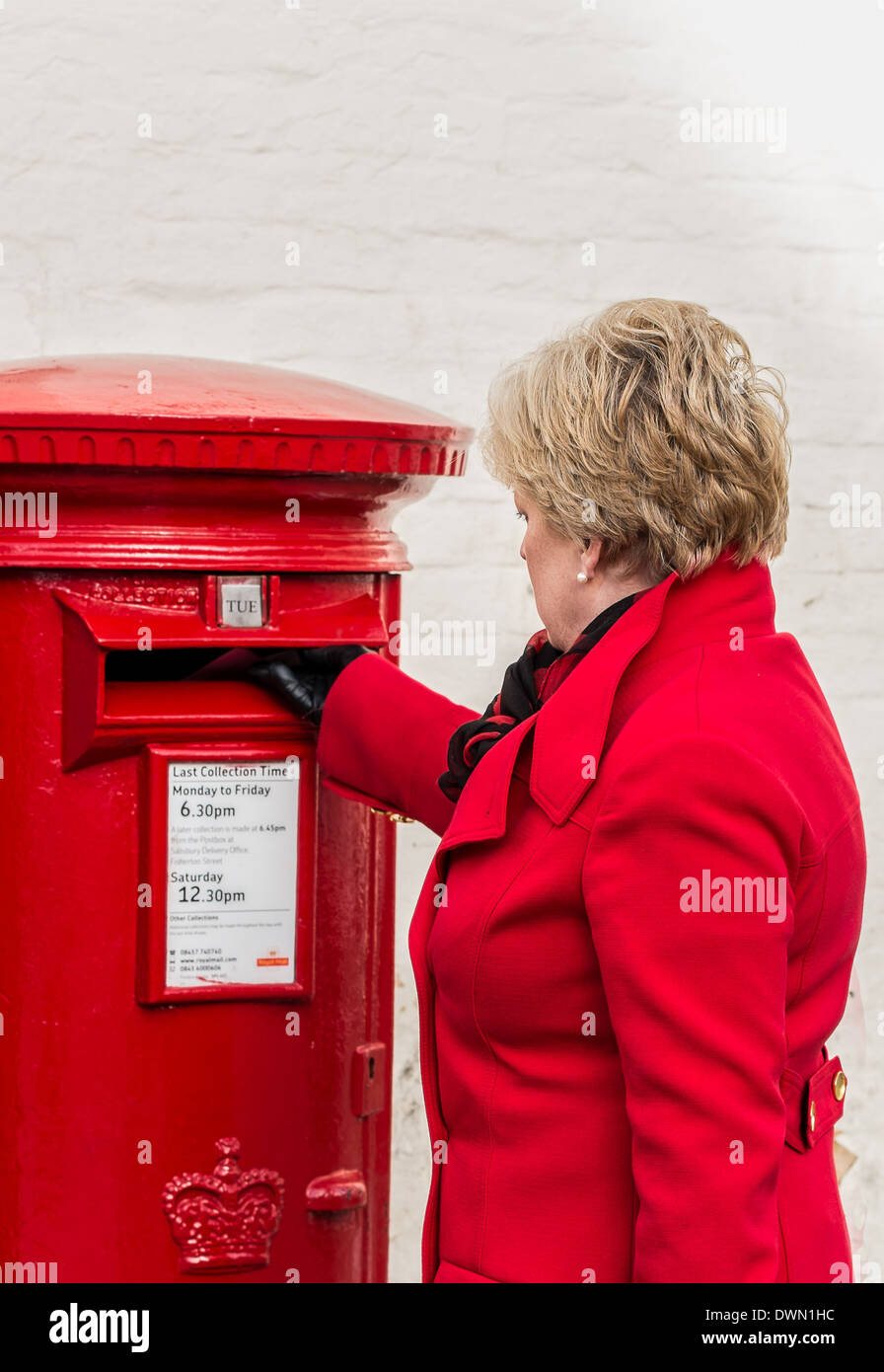 Frau in einem roten Mantel Entsendung einen Brief Stockfoto