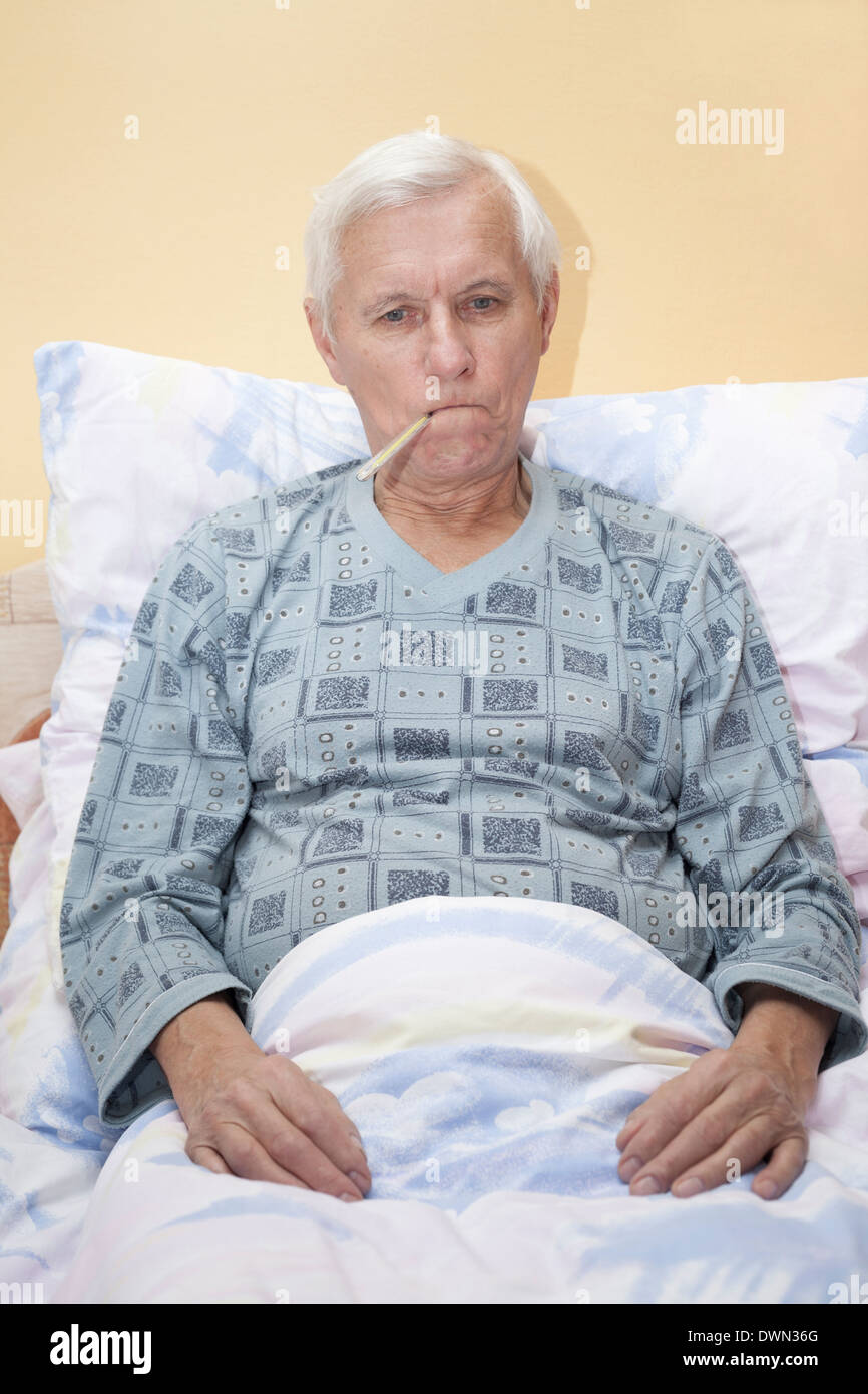 Kranker senior Mann prüfen Temperatur mit Thermometer im Bett. Stockfoto
