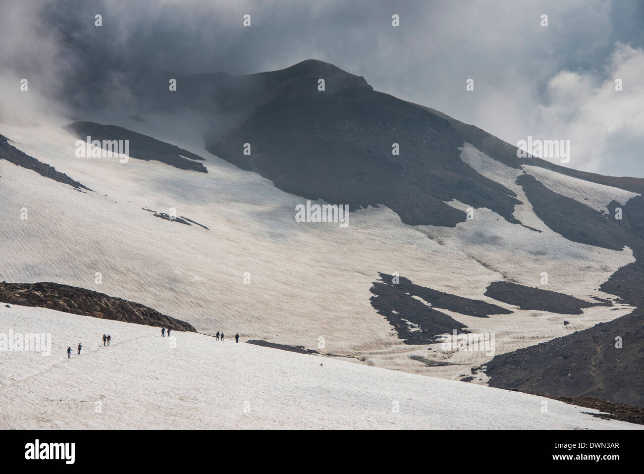 Touristen, die über ein Schneefeld, Mutnovsky Vulkan, Kamtschatka, Russland, Eurasien Stockfoto