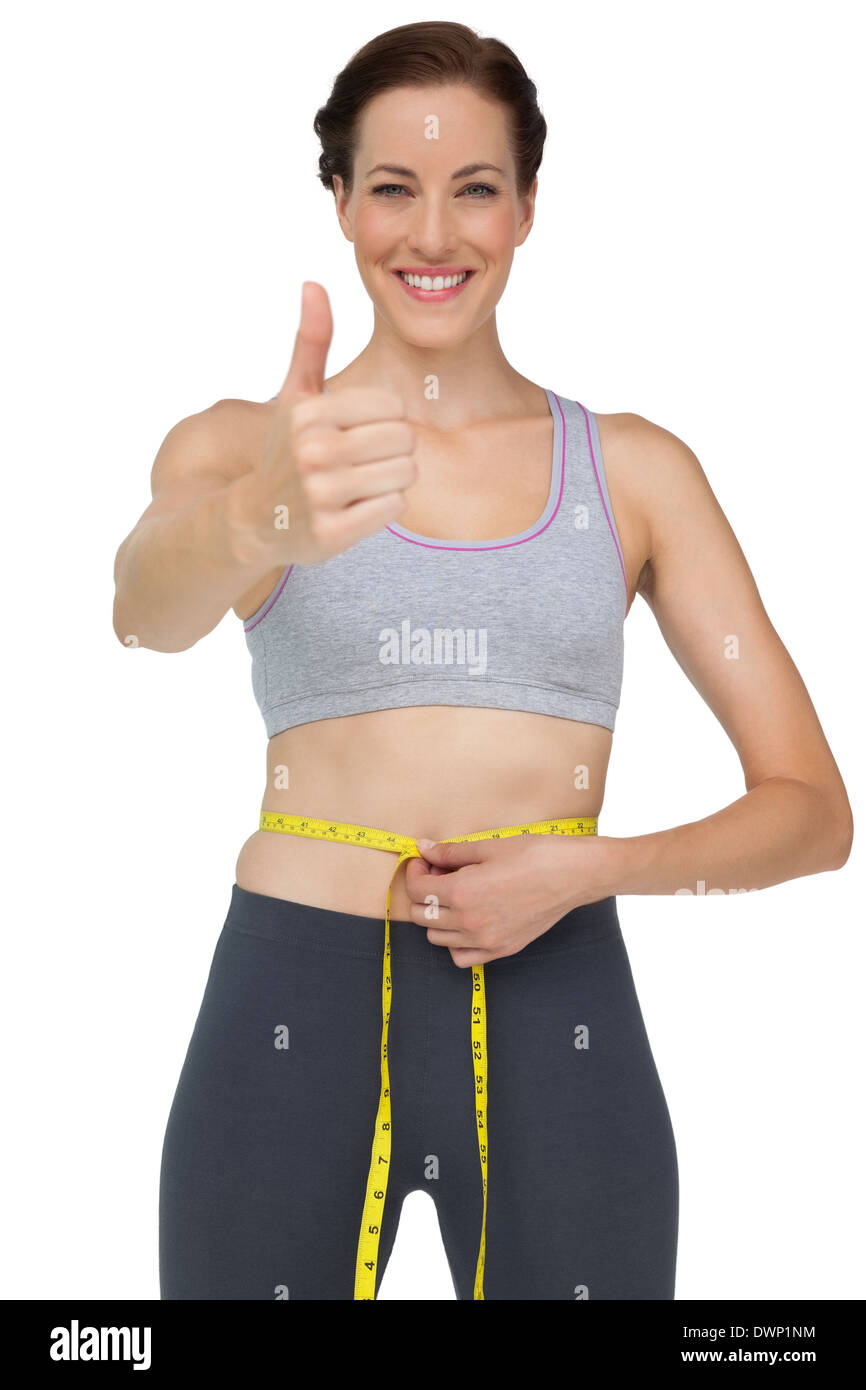 Fit Woman messen Taille während gestikulieren Daumen nach oben Stockfoto