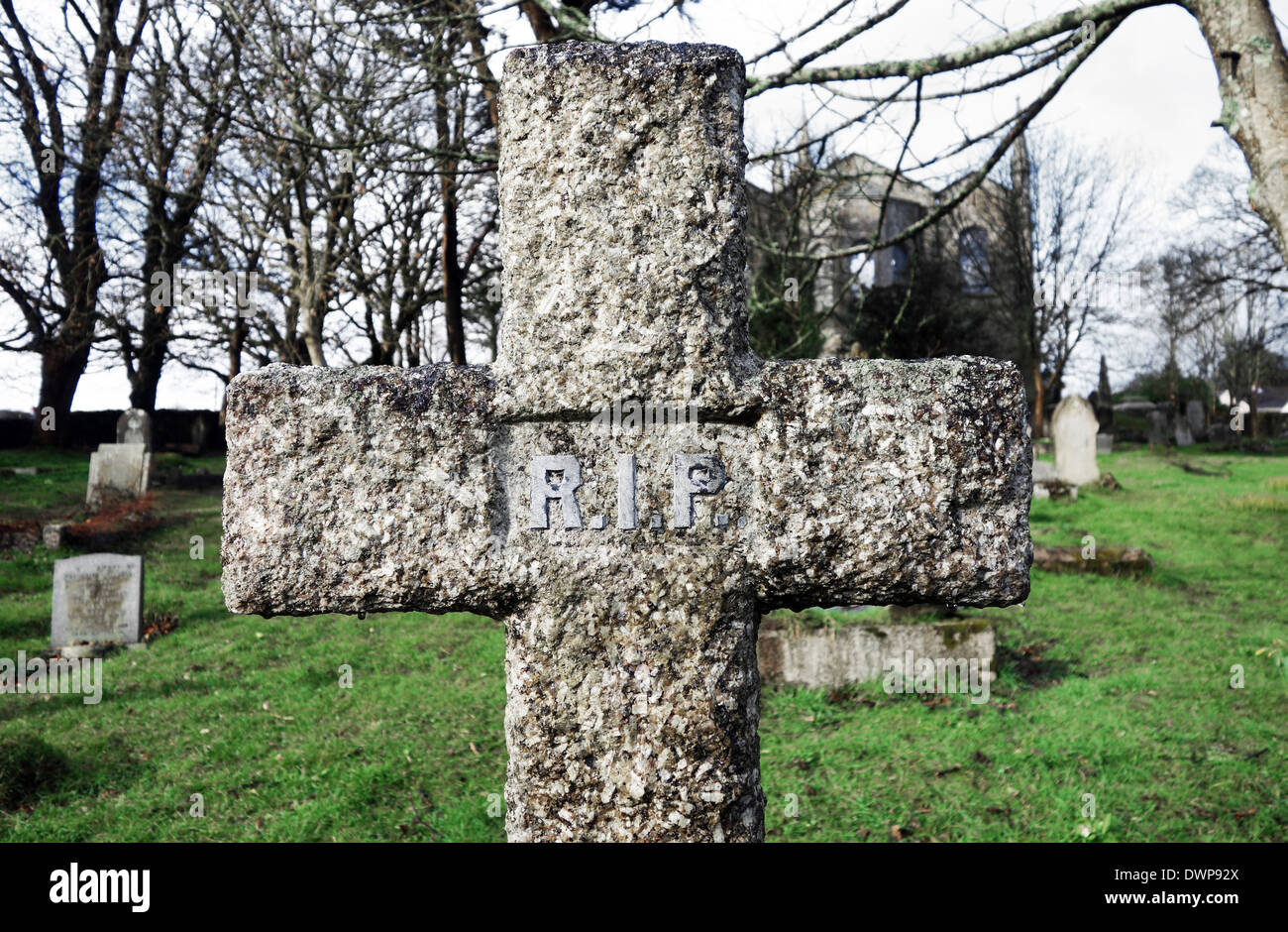 ein Steinkreuz mit R.I.P drauf auf einem Friedhof Stockfoto