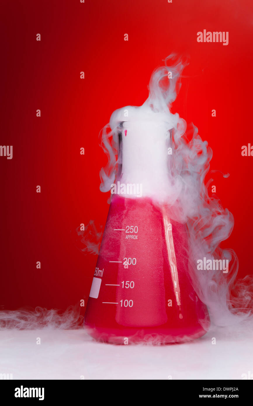 Chemie-Experiment-Kolben mit Rauch auf rotem Grund Stockfoto
