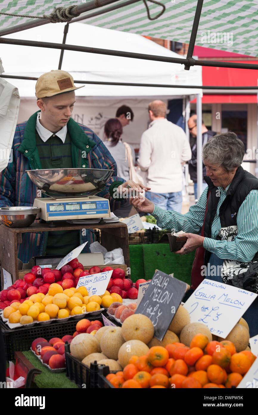 Kunden zahlen für Einkäufe am Marktstand Obst und Gemüse. Stockfoto