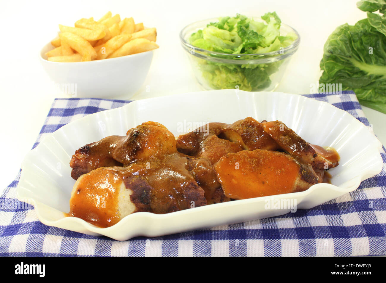 eine Currywurst mit Pommes Frites und Salat Stockfoto