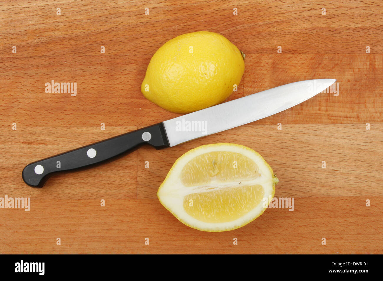 Geschnittene Zitrone und ein Messer auf einem Holzbrett Stockfoto