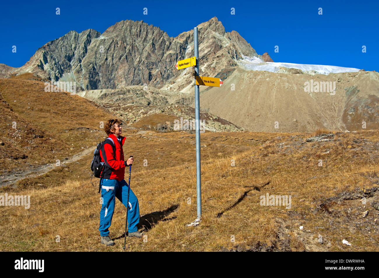 Wanderer auf einem Richtungsanzeiger vor der Bergkette Aiguilles rouges d ' Arolla, Arolla, Wallis, Schweiz Stockfoto