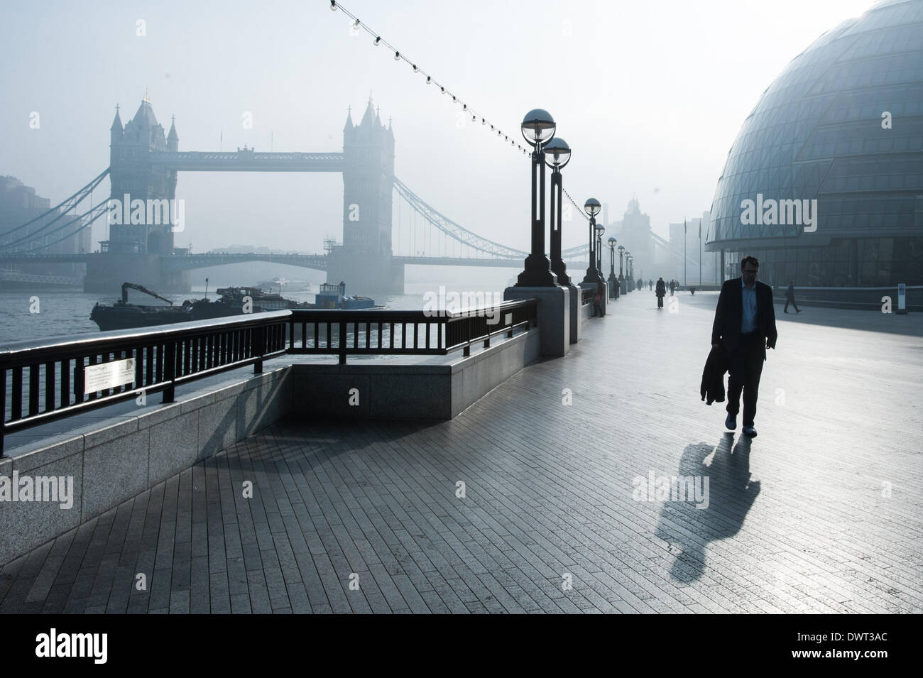 London, UK. 13. März 2014. Ein Mann geht in der Nähe von Tower Bridge als London unter dichtem Nebel aufwacht. Bildnachweis: Piero Cruciatti/Alamy Live-Nachrichten Stockfoto