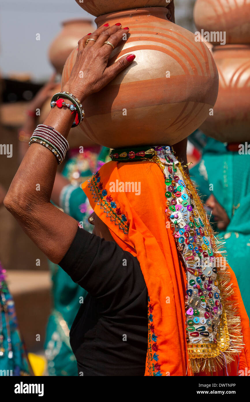 Abhaneri, Rajasthan, Indien. Frau zu Fuß mit Töpfen auf dem Kopf bei einer Feier vor der Hochzeit. Stockfoto