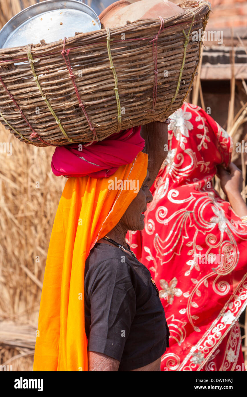 Abhaneri, Rajasthan, Indien. Frau trägt Kochen und Essen Utensilien in einem Korb auf dem Kopf. Stockfoto