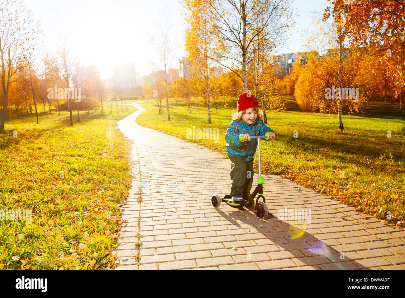 Glückliche drei Jahre alten kleinen Jungen Motorroller im Herbst Park Stockfoto