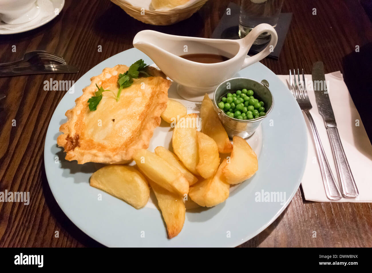 Traditionelles englisches Pub Abendessen Steak Pie Erbsen und Pommes Frites und Soße Stockfoto