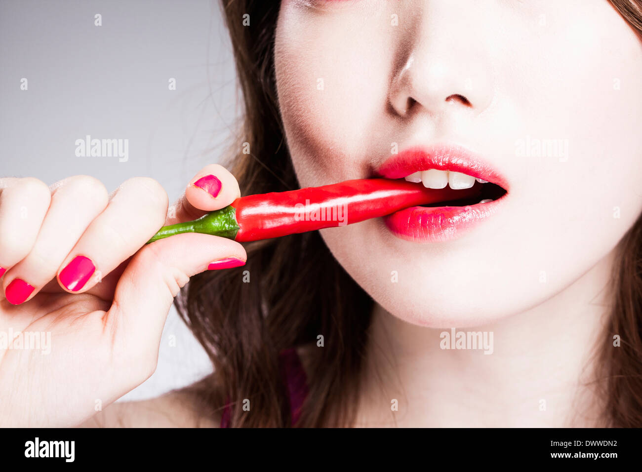 eine Frau mit schweren bilden eine Chilischote Essen Stockfoto