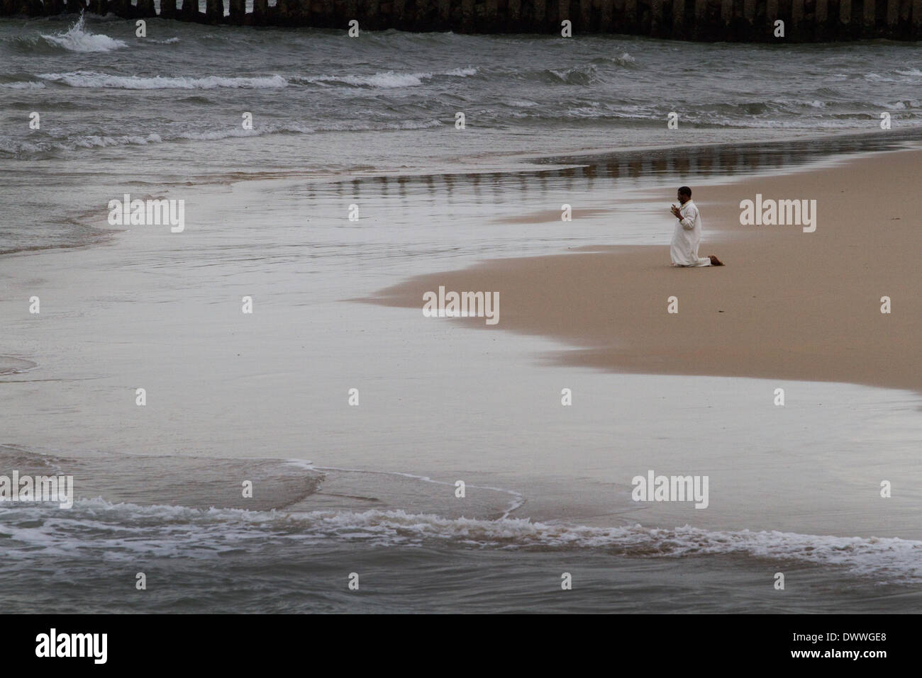 Ein Mann ist, betet kniend am Rande des Indischen Ozeans am Strand von Durban, 28. März 2010. Rogan Ward © 2010 Stockfoto