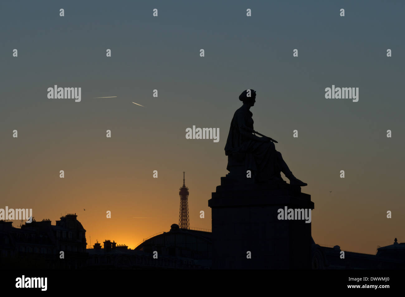 Blick auf eine teilweise silhouettierte weibliche Statue und den Eiffelturm im Hintergrund bei Sonnenuntergang in Paris, Frankreich Stockfoto